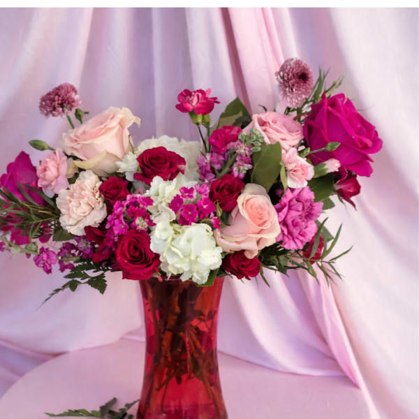 Mixed pink and white flower bouquet in a red glass vase
