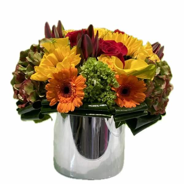 Bouquet of red roses, yellow flowers, and orange gerbera daisies in a silver vase