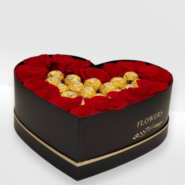 Heart-shaped black box filled with red roses surrounding gold-wrapped chocolates.