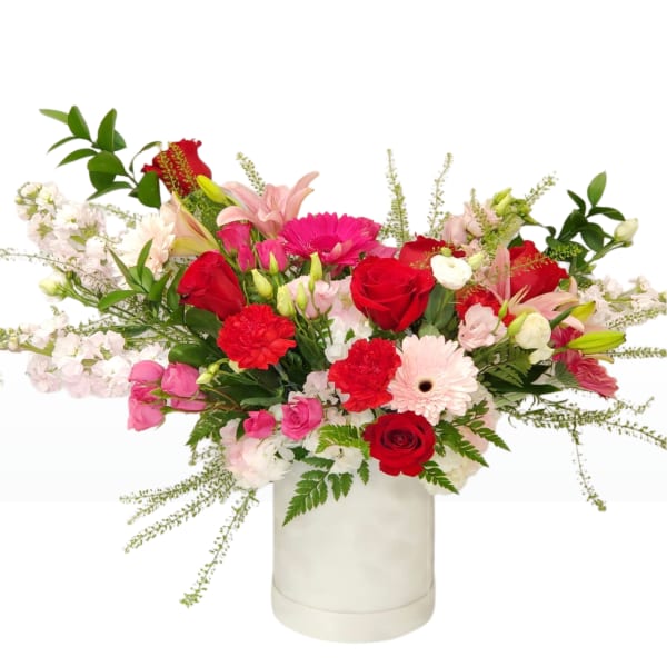 Mixed bouquet of red, pink, and white flowers in a white vase