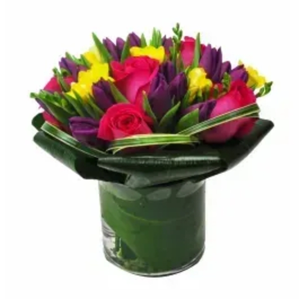 Bouquet of pink roses, purple tulips, and yellow flowers in a glass vase