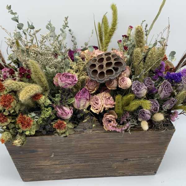 Dried flower arrangement in a wooden box with purple and peach blooms