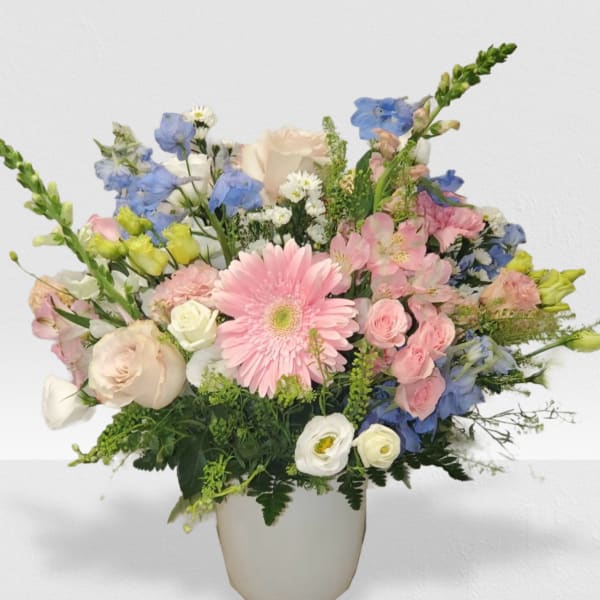 Pastel bouquet with pink gerbera, roses, and mixed blooms in a white vase