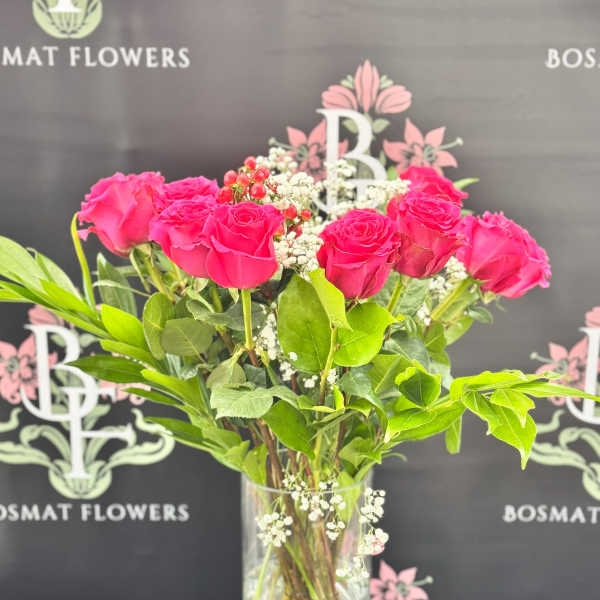 Pink roses arranged in a clear glass vase with baby's breath