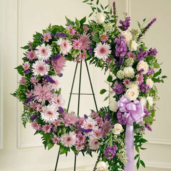 Large floral wreath on an easel with pink, purple, and white flowers