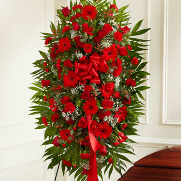 Tall standing spray of red flowers with a ribbon bow