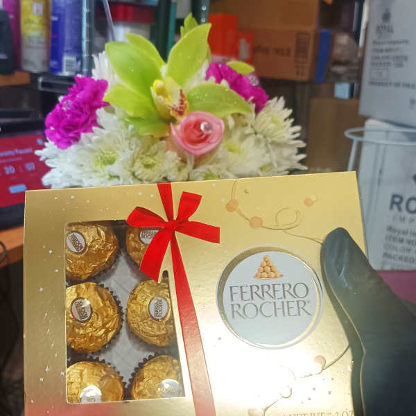 Ferrero Rocher chocolate box held in front of a small flower arrangement