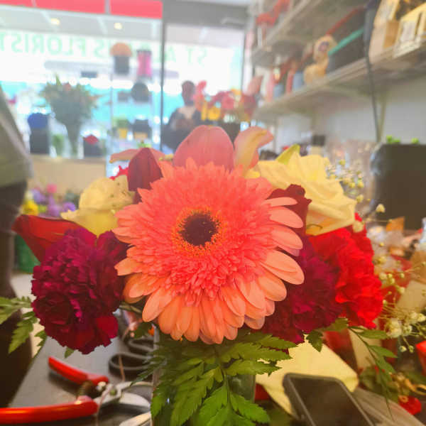 Bright mixed bouquet with a pink gerbera daisy in a glass vase