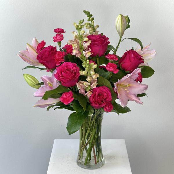 Pink roses and lilies arranged in a clear glass vase