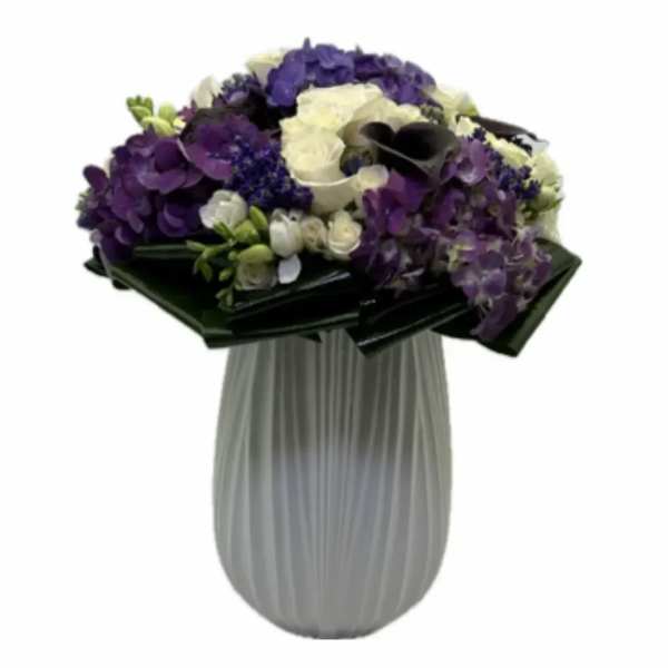 Purple and white floral arrangement in a gray vase