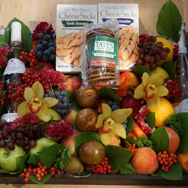 Fruit and snack gift tray with wine bottles and yellow orchids