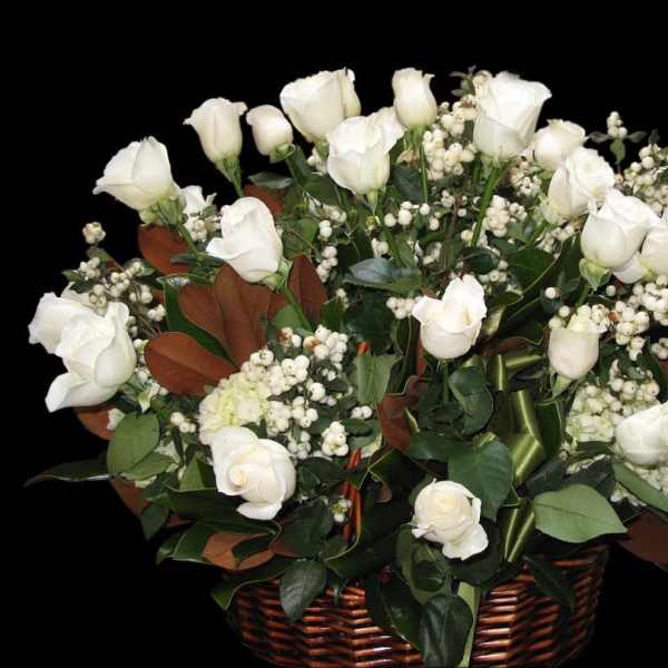 White roses and berry clusters arranged in a wicker basket