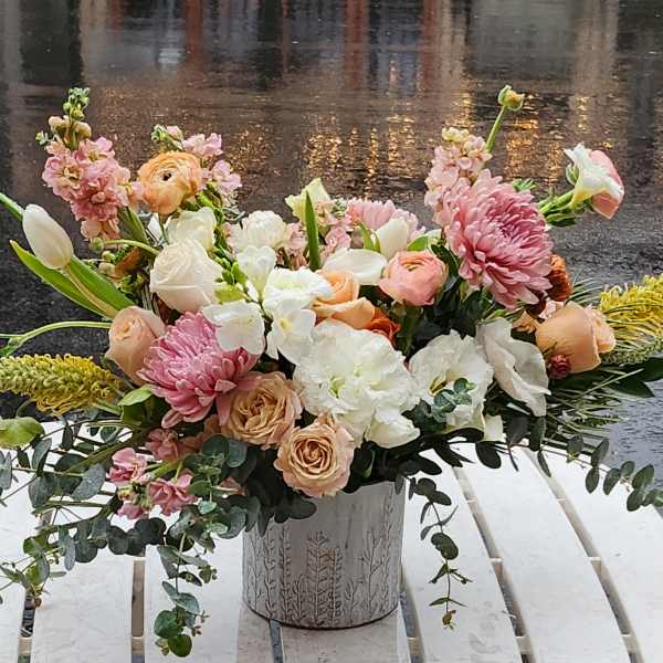 Mixed pastel bouquet in a decorative metal vase on a white table