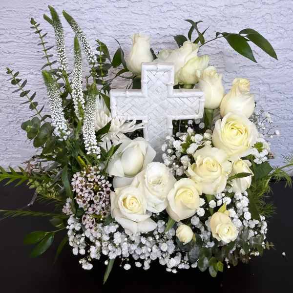 White roses and a cross centerpiece with greenery