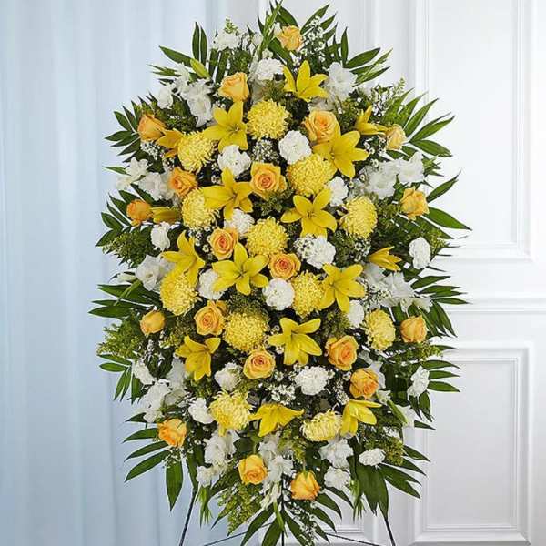 Tall yellow and white standing spray with lilies, roses, and carnations on a metal easel