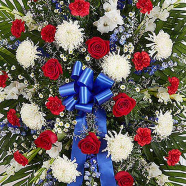Standing floral spray with red roses, white blooms, and blue ribbon