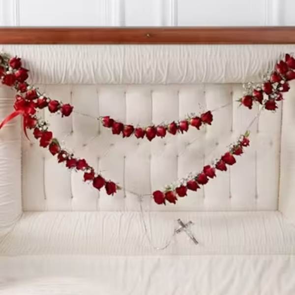 Red rose garlands draped across a white tufted headboard