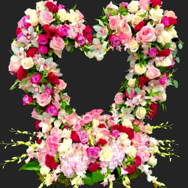 Heart-shaped floral arrangement of pink, white, and red roses