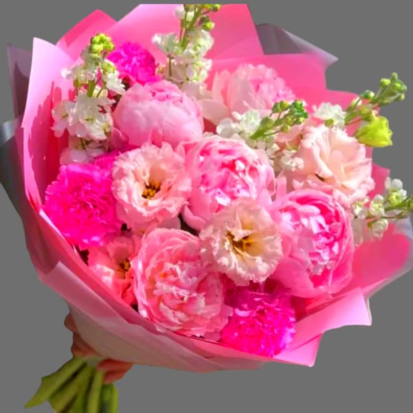 Pink bouquet of peonies and carnations wrapped in bright pink paper