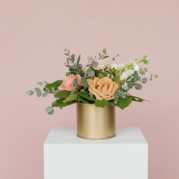 Peach and pink rose arrangement in a gold cylinder vase
