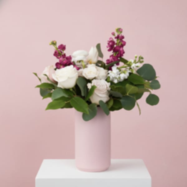 Pink and white floral arrangement in a tall pink vase