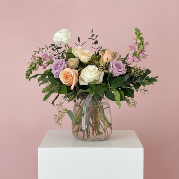 Mixed roses and lavender flowers in a clear glass vase