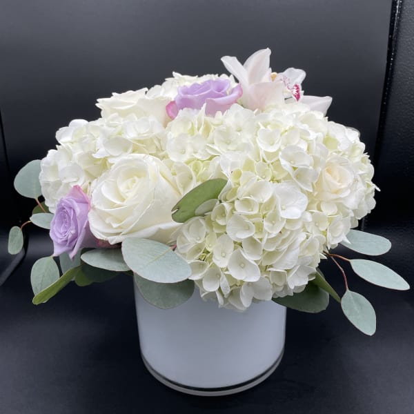 White hydrangea and roses in a white vase with pale purple accents