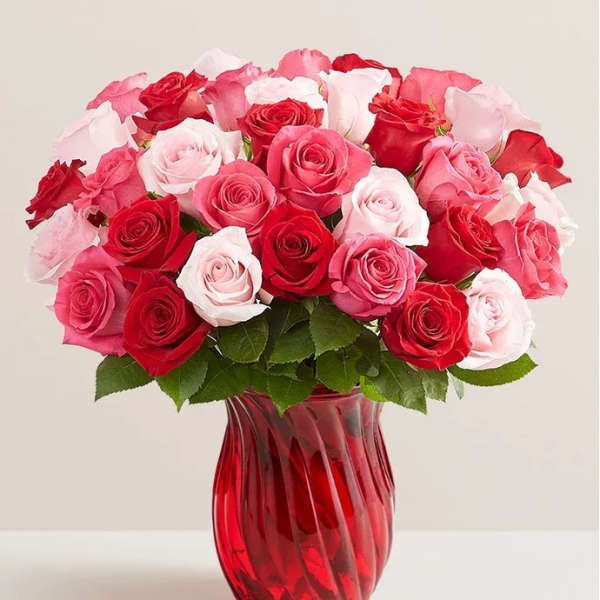 Bouquet of red, pink, and white roses in a red glass vase