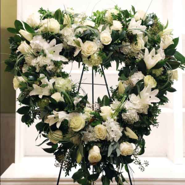 Heart-shaped white floral wreath on a stand