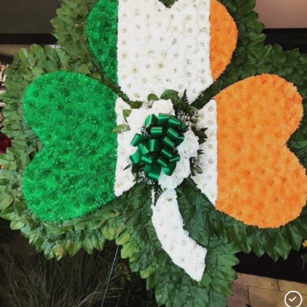 Large floral tribute in green, white, and orange with a bow