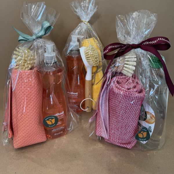 Three wrapped cleaning gift sets with soap bottles and scrub brushes