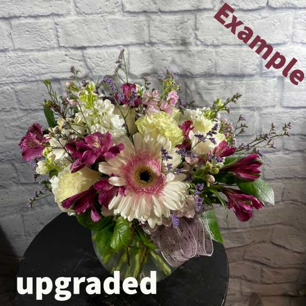 Mixed bouquet with a pink gerbera daisy and purple blooms in a glass vase