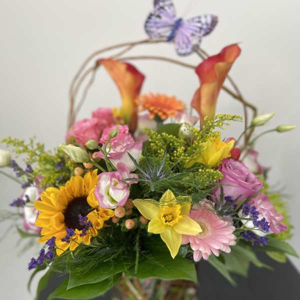 Mixed bouquet in a glass vase with sunflowers, pink blooms, and calla lilies