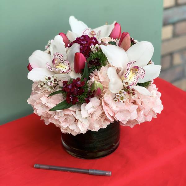 Pink and white floral arrangement in a black vase