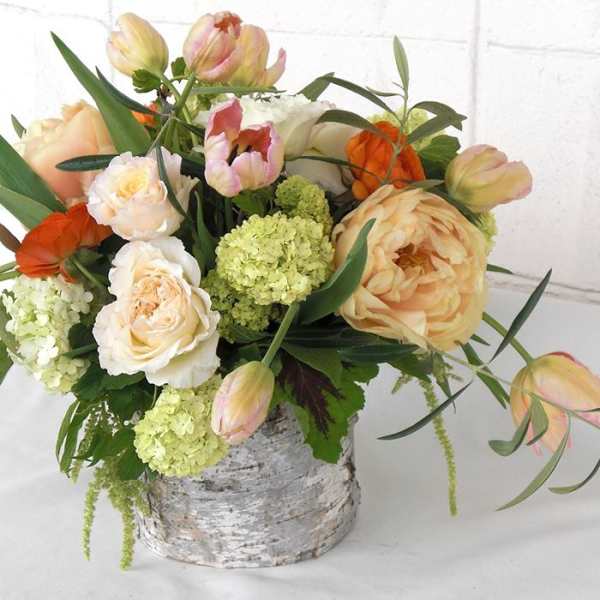 Peach and white floral arrangement in a birch-style container