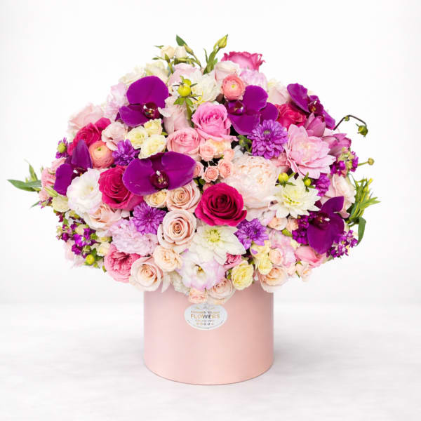 Large bouquet of pink, white, and purple flowers in a pink hat box