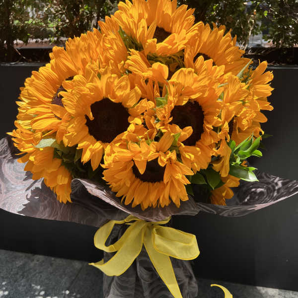 Bouquet of bright yellow sunflowers wrapped with a yellow ribbon