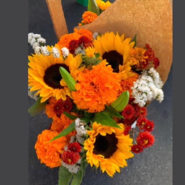 Bouquet of sunflowers, orange marigolds, and red flowers wrapped in brown paper