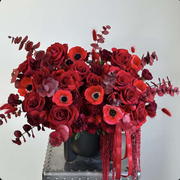 Red rose bouquet with poppies in a black vase