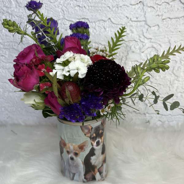 Mixed bouquet in a dog-printed container with pink, purple, white, and red blooms