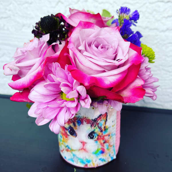 Pink roses and purple daisies in a cat-printed vase