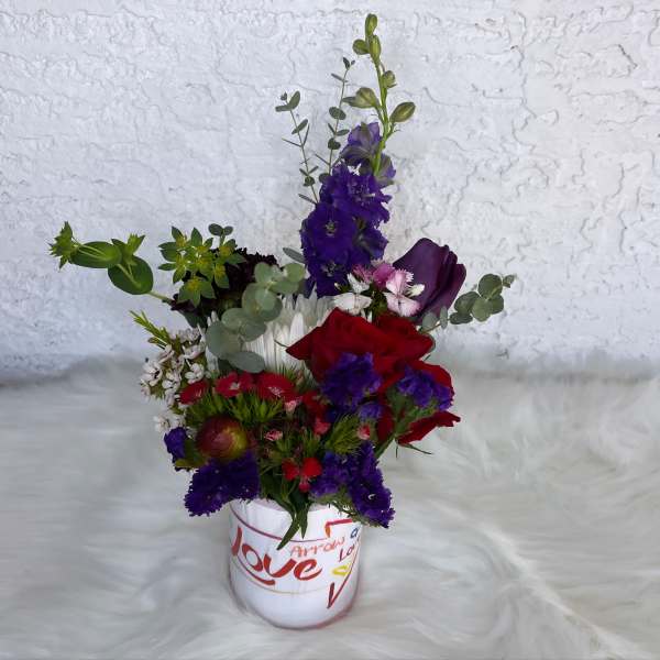 Mixed bouquet in a white vase with red, purple, and white flowers