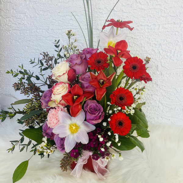 Mixed bouquet with red gerberas, roses, and white daffodils in a red vase