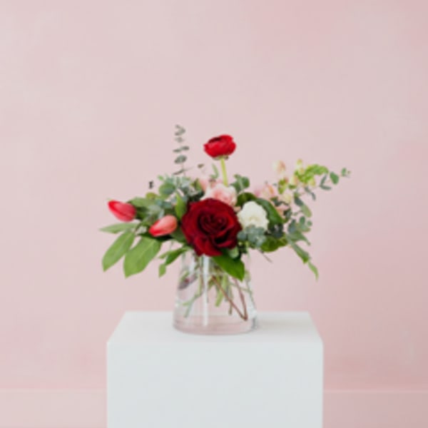 Red roses and pink tulips in a clear glass vase