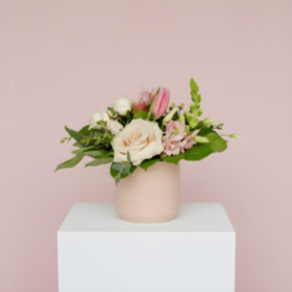 Pink and white floral arrangement in a blush vase