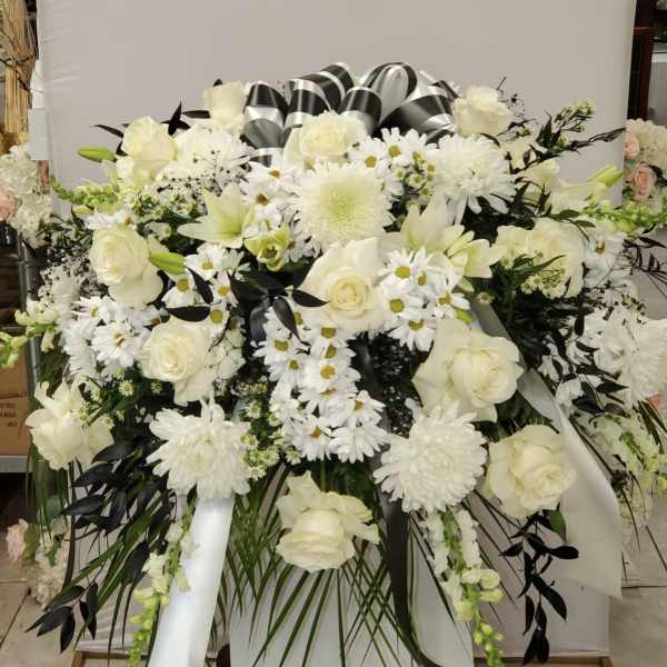 White floral funeral spray with roses, daisies, and lilies