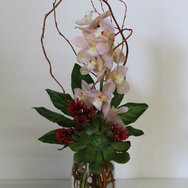 Pink orchids arranged in a glass vase with succulents and red accents