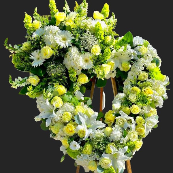 Heart-shaped floral wreath of white and yellow flowers on an easel