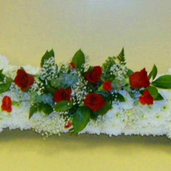White floral arrangement shaped like a bone with red roses in the center