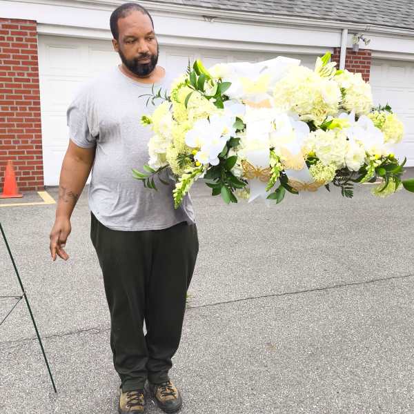 Man holding a large white floral spray with ribbons and butterflies